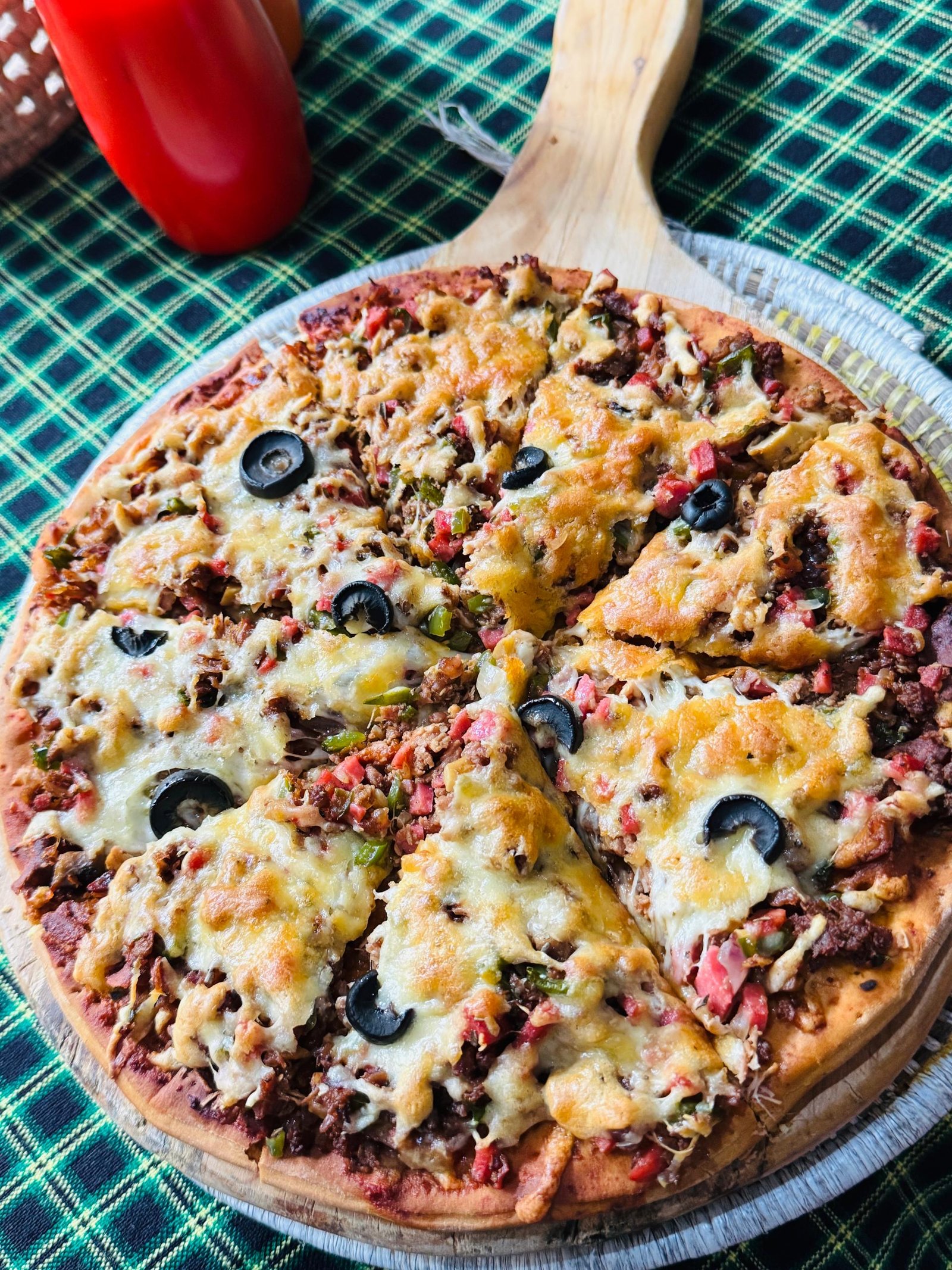 A freshly baked pizza served on a wooden board at the eco camp